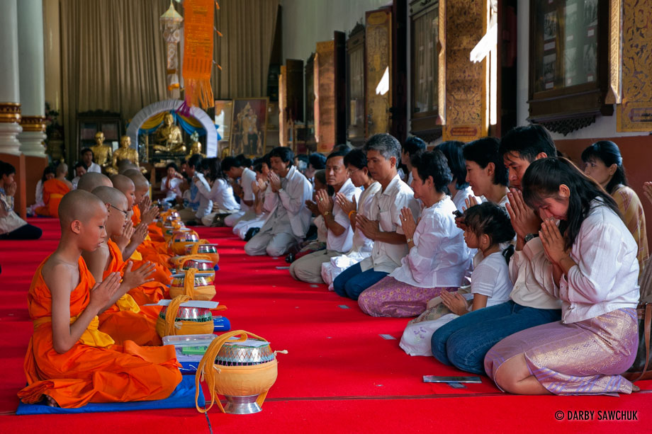 Novice Buddhist monks pray with their families at their ordination at Wat Chedi Luang in Chiang Mai, Thailand.