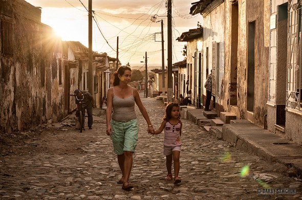 A mother and daughter walk the cobbled streets of Trinidad, Cuba at sunset.
