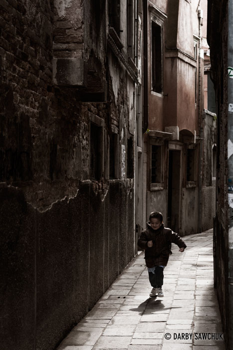 A young boy runs through a narrow street in the Castello district in Venice, Italy.
