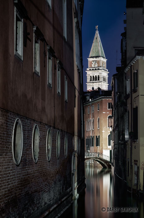 St. Mark's Campanile rises over one of the small canals in the San Marco district at night.