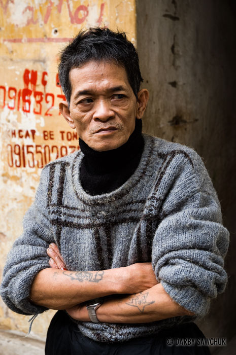 A man leans against a wall in the old quarter of Hanoi.